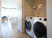 Thumbnail 11 of 47 - a front loading washer and dryer in a living room with a laundry room