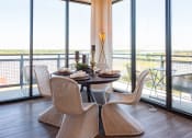 Thumbnail 5 of 47 - Dog-Friendly Apartments in Downtown Memphis, TN - The Landing - Dining Room with Hardwood Flooring, Round Table with Wicker Chairs, and Floor-to-Ceiling Window Walls.