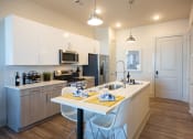 Thumbnail 12 of 47 - a kitchen with an island and a table with white chairs
