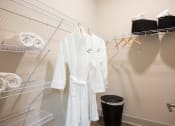 Thumbnail 20 of 47 - a laundry room with a white robe and a rack with towels