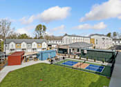 Thumbnail 25 of 29 - A tennis court is surrounded by a green fence and a building.