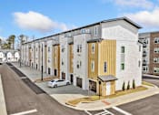 Thumbnail 27 of 29 - A row of modern townhouses with a white car parked in front of the first one.