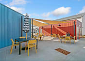 Thumbnail 26 of 29 - A patio with a table and chairs is surrounded by a blue wall.