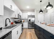 Thumbnail 3 of 29 - A modern kitchen with white cabinets and a wooden floor.