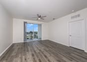 Thumbnail 23 of 35 - A room with a ceiling fan and sliding glass doors.