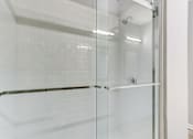 Thumbnail 14 of 31 - A white tiled shower with a glass door.