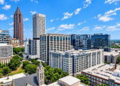 Thumbnail 4 of 33 - A cityscape with a mix of modern and older buildings under a clear blue sky.