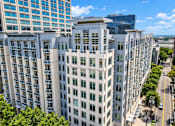 Thumbnail 6 of 33 - A tall white building with many windows is in the foreground of a city street.