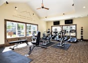 Thumbnail 28 of 42 - A gym with a variety of equipment including treadmills, weights, and a bench.