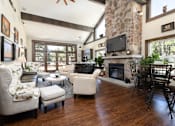 Thumbnail 26 of 42 - A living room with a stone fireplace and a flat screen TV mounted above it.