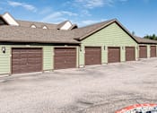 Thumbnail 34 of 42 - A parking lot with a green building and brown garage doors.