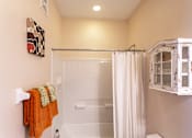 Thumbnail 13 of 25 - A bathroom with a shower curtain and a towel hanging on the wall.