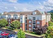Thumbnail 21 of 25 - A large apartment complex with a parking lot in front.