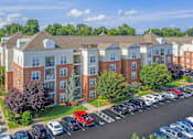 Thumbnail 20 of 25 - A large apartment complex with a parking lot in front.