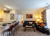 Thumbnail 9 of 25 - Johnson City, TN, Apartments with In-Unit Washer and Dryer - University Edge - Open Living Room With Breakfast Bar Seating, Leather Sofa, Table Lamp, Wall Art, And Large Window With Curtains.