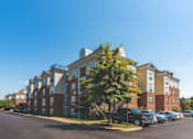 Thumbnail 23 of 25 - A large apartment complex with a parking lot in front.