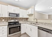 Thumbnail 1 of 18 - A kitchen with white cabinets and a black stove top oven.