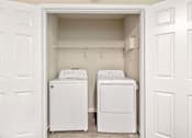 Thumbnail 8 of 18 - Two white washing machines in a small laundry room.