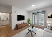 Thumbnail 14 of 28 - Two-Bedroom Luxury Apartments in Huntsville, AL - The Kelvin - Living Room with Luxury Vinyl Tile Flooring, Area Rug, Sofa, Glass-Top Coffee Table, Side Table with Lamp, Media Cabinet, Wall-Mounted TV, and French Doors with Access to Patio.
