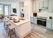 Thumbnail 70 of 70 - A kitchen with white cabinets and a white island with a sink.