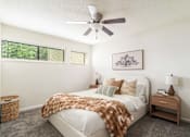 Thumbnail 8 of 35 - A bedroom with a bed covered in a brown blanket and a ceiling fan above it.