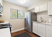 Thumbnail 6 of 35 - A kitchen with a stainless steel refrigerator and white cabinets.