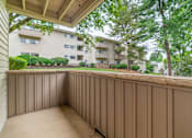 Thumbnail 10 of 35 - A balcony with a brown railing and a view of apartment buildings.