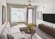 Thumbnail 3 of 70 - A living room with a grey couch, a wooden coffee table, and a flat screen TV mounted on the wall.