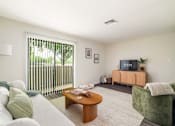 Thumbnail 1 of 35 - A living room with a sofa, a coffee table, and a television.