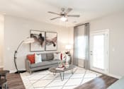 Thumbnail 6 of 50 - Alcoa, TN, Luxury Apartments with In-Unit Washer and Dryer - Vintage Hunters Crossing - Living Room with Hardwood-Inspired Flooring, Couch, Coffee Table, Floor Lamp, Wall Arts, and Ceiling Fan.
