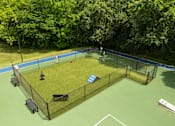 Thumbnail 29 of 35 - A tennis court surrounded by a fence with a bench and a trash can.