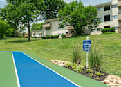 Thumbnail 30 of 35 - A blue sign is on a pole next to a green and blue track.