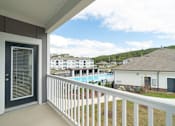 Thumbnail 17 of 41 - A balcony with a view of a pool and houses.