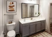 Thumbnail 15 of 70 - A bathroom with a toilet, sink, and a mirror.