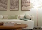 Thumbnail 5 of 35 - A living room with a white couch, a wooden coffee table, and two abstract paintings on the wall.