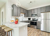 Thumbnail 12 of 41 - A kitchen with a granite countertop and stainless steel appliances.