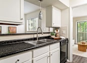 Thumbnail 3 of 35 - A kitchen with black countertops and white cabinets.
