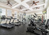 Thumbnail 11 of 30 - a gym with cardio machines and ceiling fans