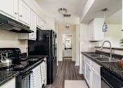 Thumbnail 2 of 35 - A kitchen with black appliances and white cabinets.
