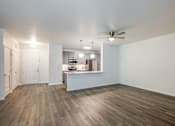 Thumbnail 8 of 35 - A spacious kitchen and living room with wood flooring and white walls.