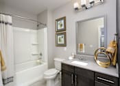 Thumbnail 12 of 31 - A bathroom with a white toilet, a white sink, and a white bathtub.