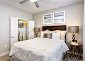 Thumbnail 11 of 31 - A bedroom with a large bed and a ceiling fan.