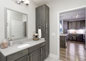 Thumbnail 7 of 31 - A bathroom with a sink, mirror, and wooden cabinets.