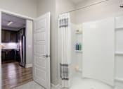 Thumbnail 9 of 31 - A white bathroom with a shower curtain and a white door.