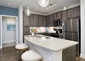 Thumbnail 2 of 31 - A kitchen with a white counter top and a refrigerator.