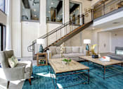 Thumbnail 14 of 31 - A living room with a staircase and a grey couch.