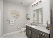 Thumbnail 8 of 31 - A bathroom with a toilet, sink, and a mirror.