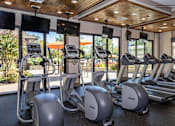 Thumbnail 13 of 31 - a gym with cardio equipment and windows
