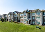 Thumbnail 24 of 28 - an exterior view of an apartment building with a green lawn