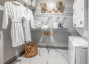 Thumbnail 20 of 48 - a small laundry room with white robes and a washing machine and a basket